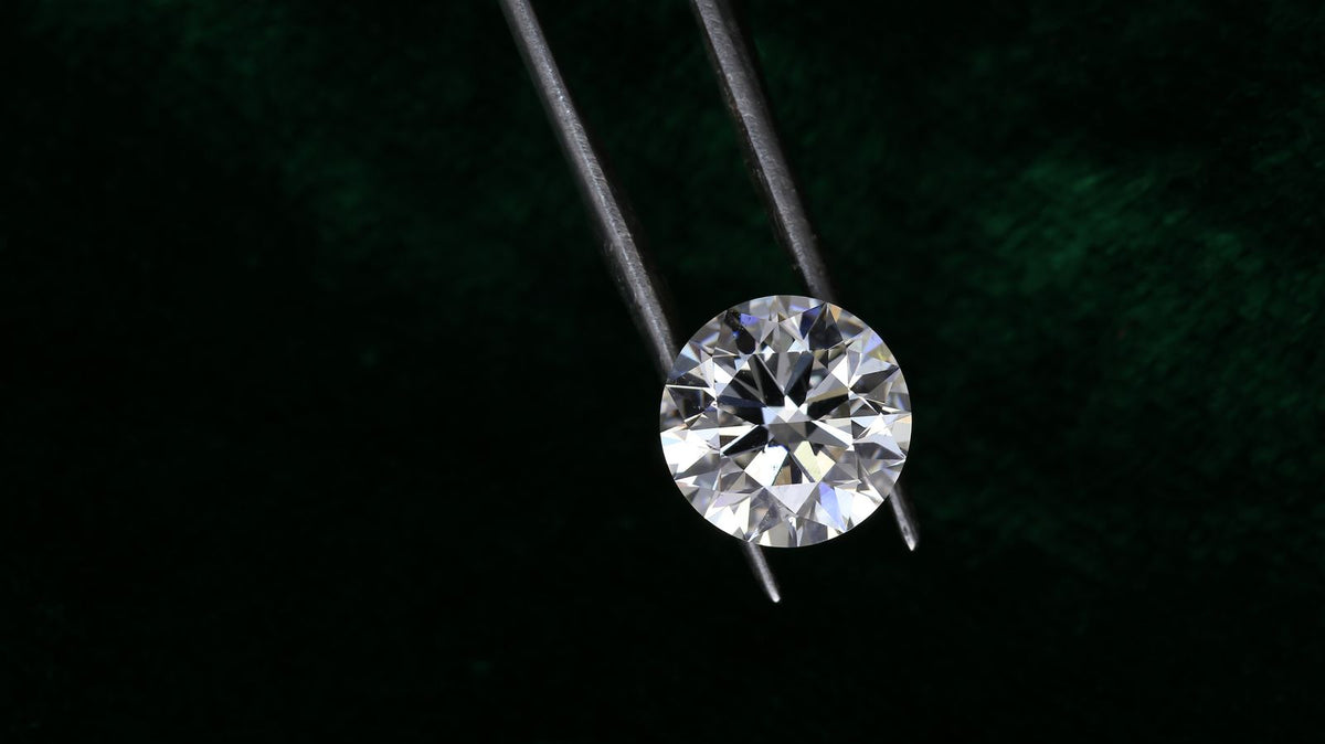 Round brilliant diamond held in tweezers for grading