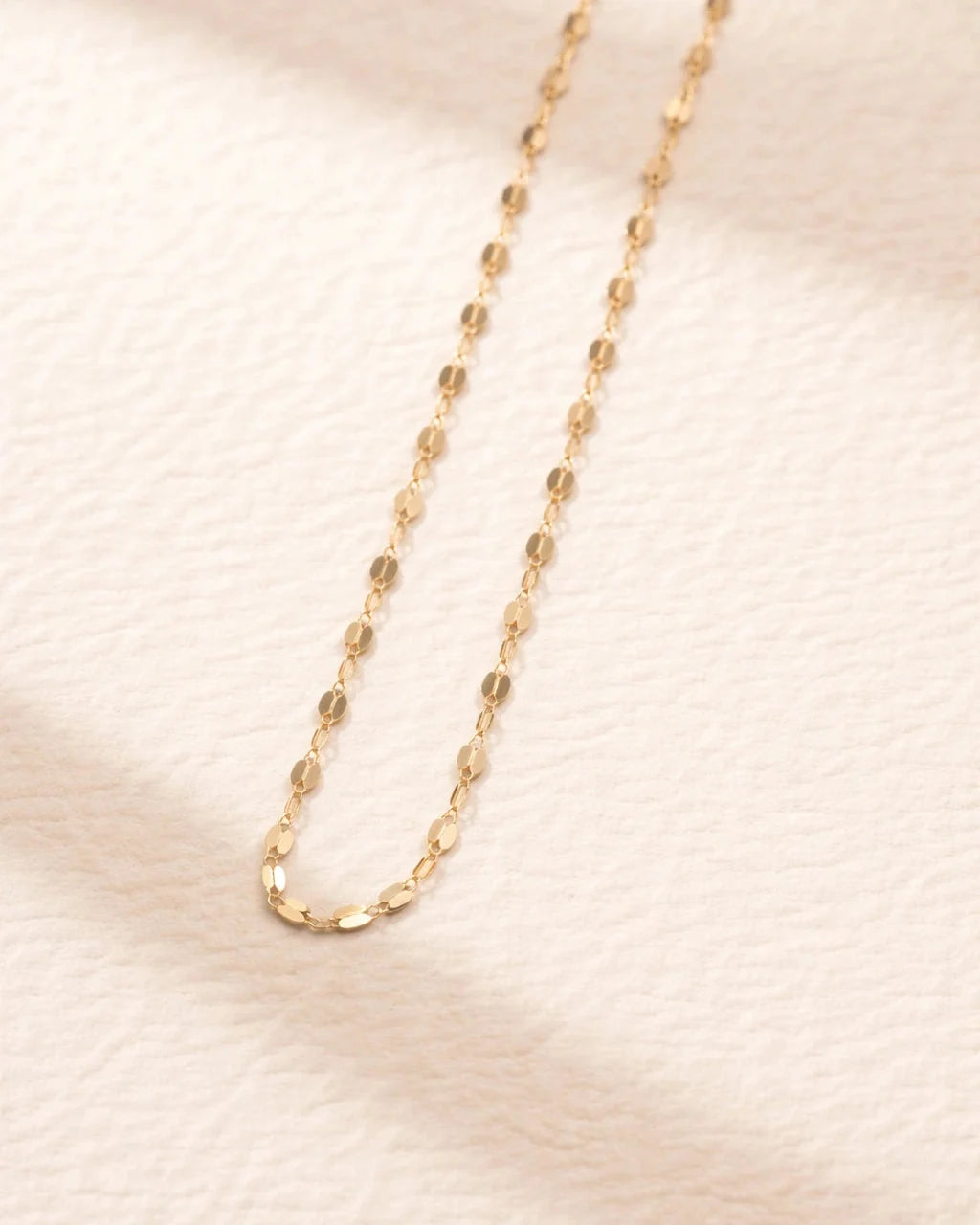 Gold chain necklace on a soft beige background