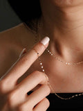 Close-up of a delicate gold chain necklace being adjusted on a person's neck.
