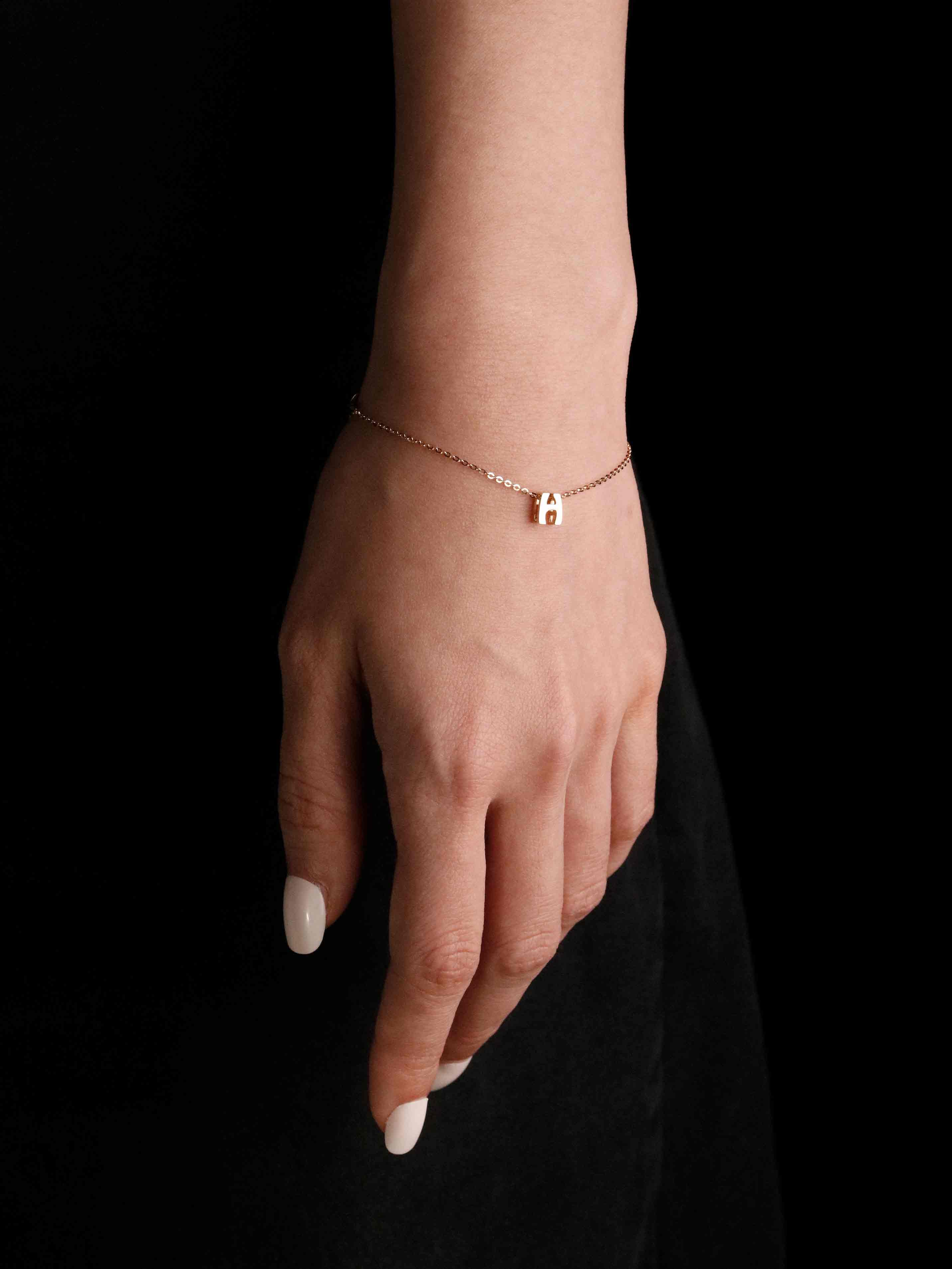 Hand wearing a delicate bracelet on a black background
