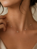 A delicate gold chain necklace with small, clear crystal butterfly charms worn by a model. The shot is a close-up of the model's neck and upper chest, highlighting how the fine chain drapes against the skin.