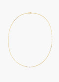 A delicate gold chain necklace with small, evenly spaced black beads, displayed in an oval shape against a solid white background.