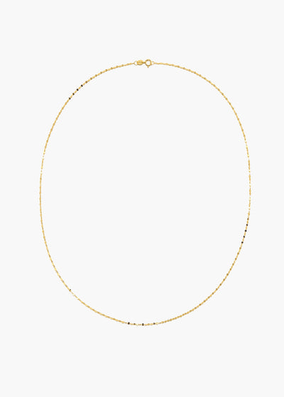 A delicate gold chain necklace with small, evenly spaced black beads, displayed in an oval shape against a solid white background.
