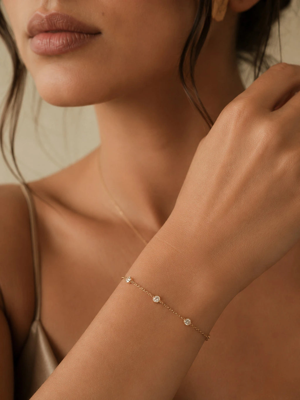 Close-up of 18K solid gold diamond station bracelet on wrist, three bezel-set round diamonds on fine cable chain, hallmarked au750