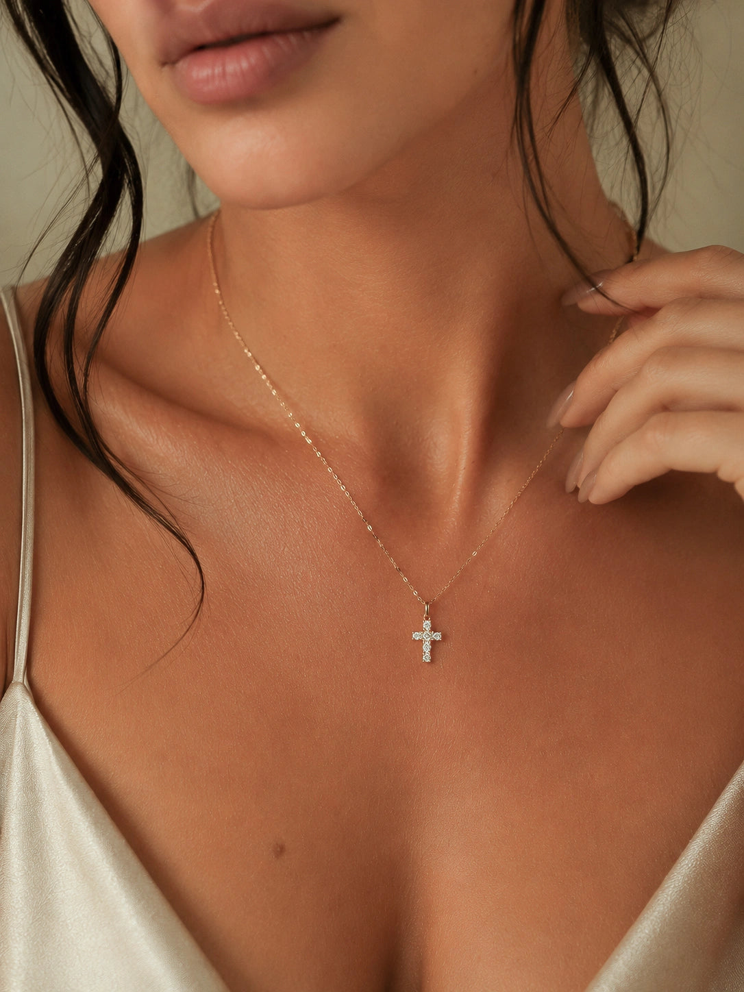 Close-up of a woman wearing a delicate necklace with a cross pendant.