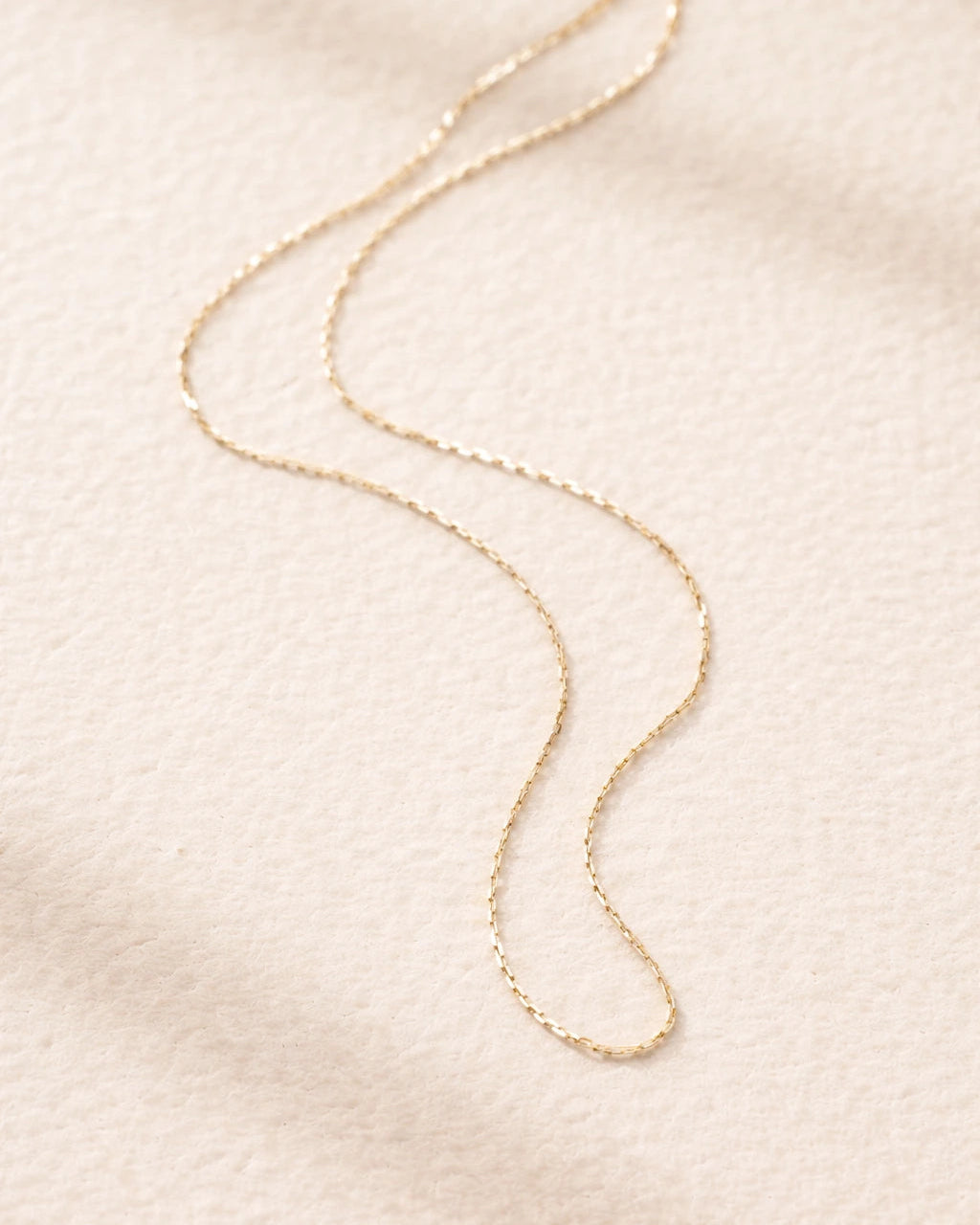 Gold necklace on a soft beige background