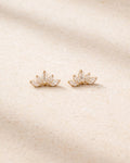 Pair of gold earrings with a floral design on a beige background