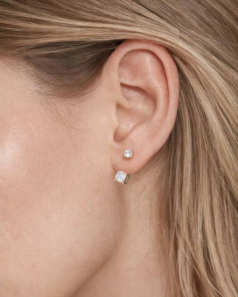Close-up of a person wearing two diamond stud earrings.