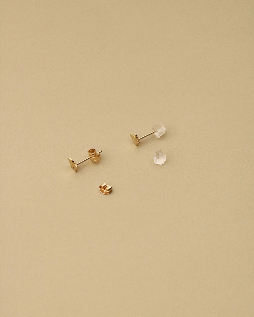 Gold earrings on a beige background