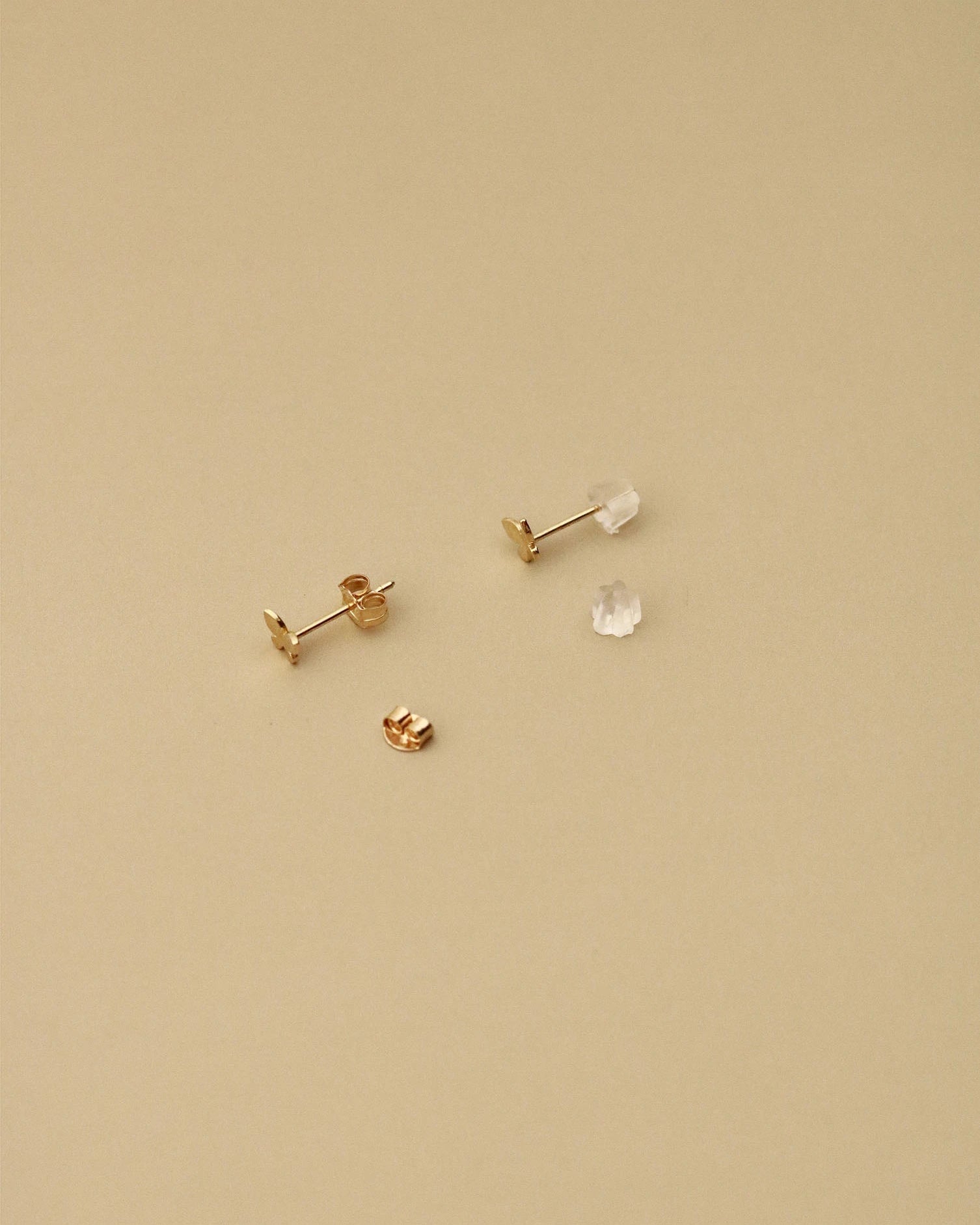 Gold earrings on a beige background