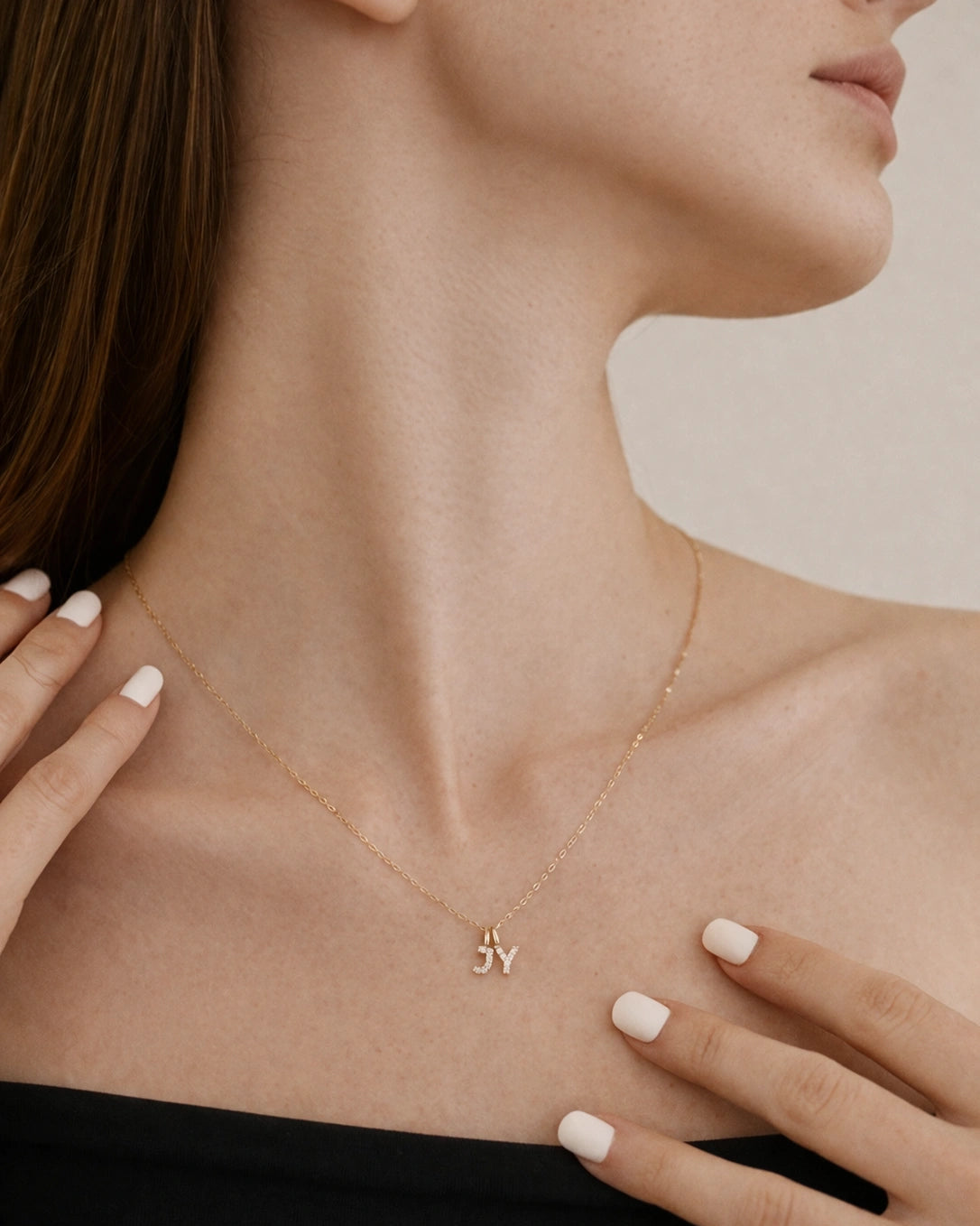 Gold necklace with a small pendant worn by a person, with a neutral background