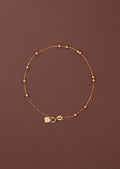 18K solid gold satellite bead station bracelet full view on dark burgundy background, FSS heart charm tag and spring ring clasp visible, hallmarked au750