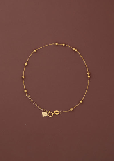 18K solid gold satellite bead station bracelet full view on dark burgundy background, FSS heart charm tag and spring ring clasp visible, hallmarked au750