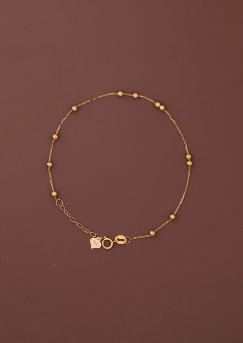 18K solid gold satellite bead station bracelet full view on dark burgundy background, FSS heart charm tag and spring ring clasp visible, hallmarked au750