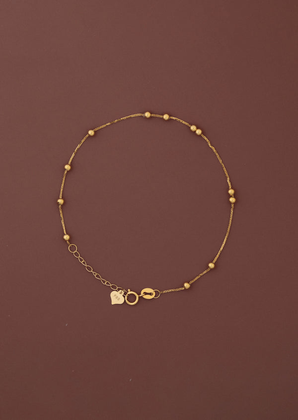 18K solid gold satellite bead station bracelet full view on dark burgundy background, FSS heart charm tag and spring ring clasp visible, hallmarked au750