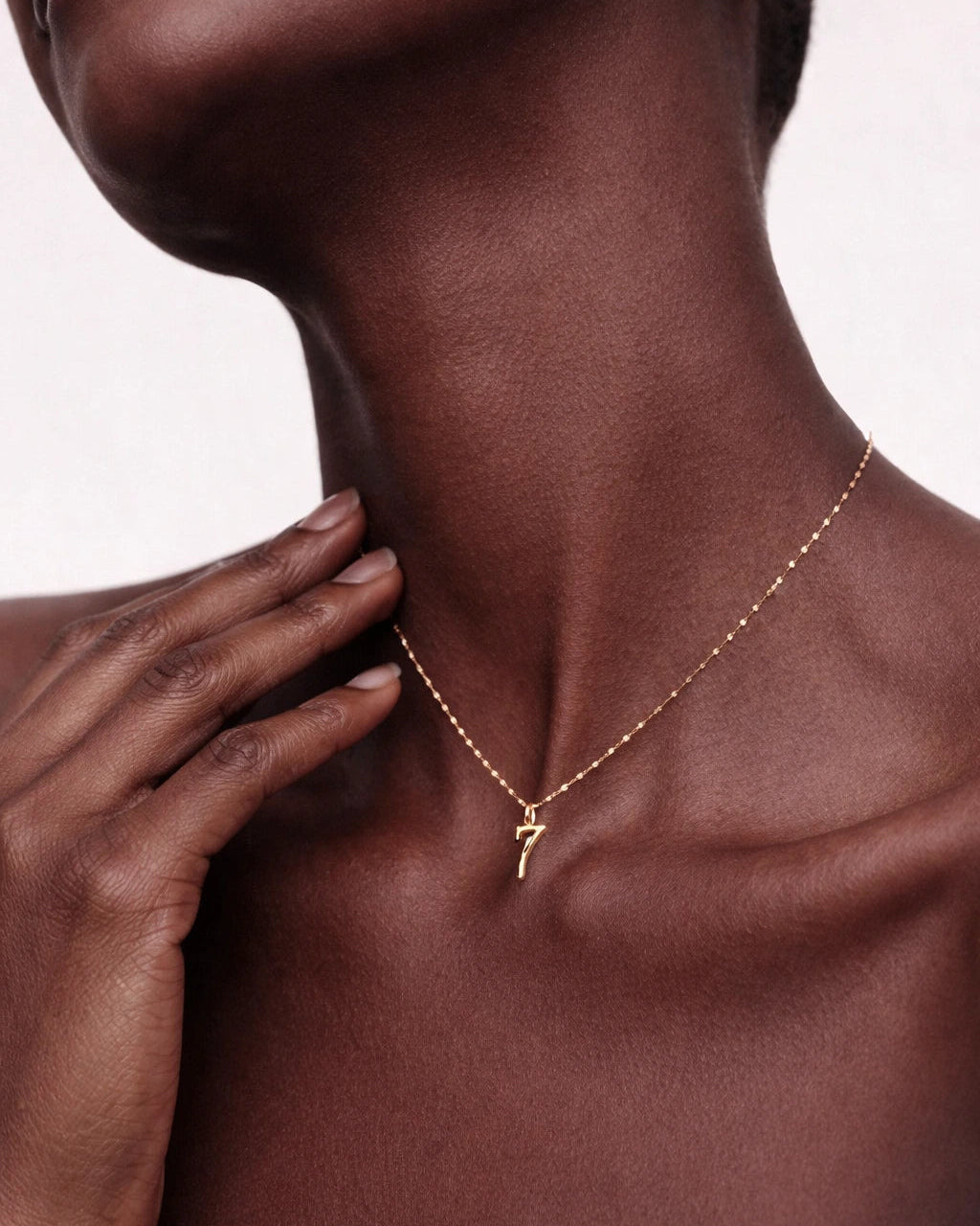 Necklace with a pendant worn by a person, with a hand touching the neck.