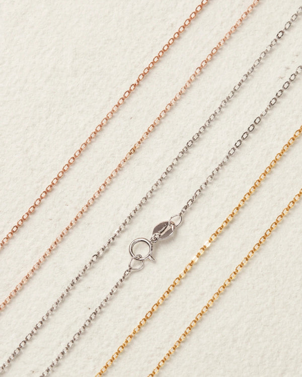 Three gold chains of different colors on a light background