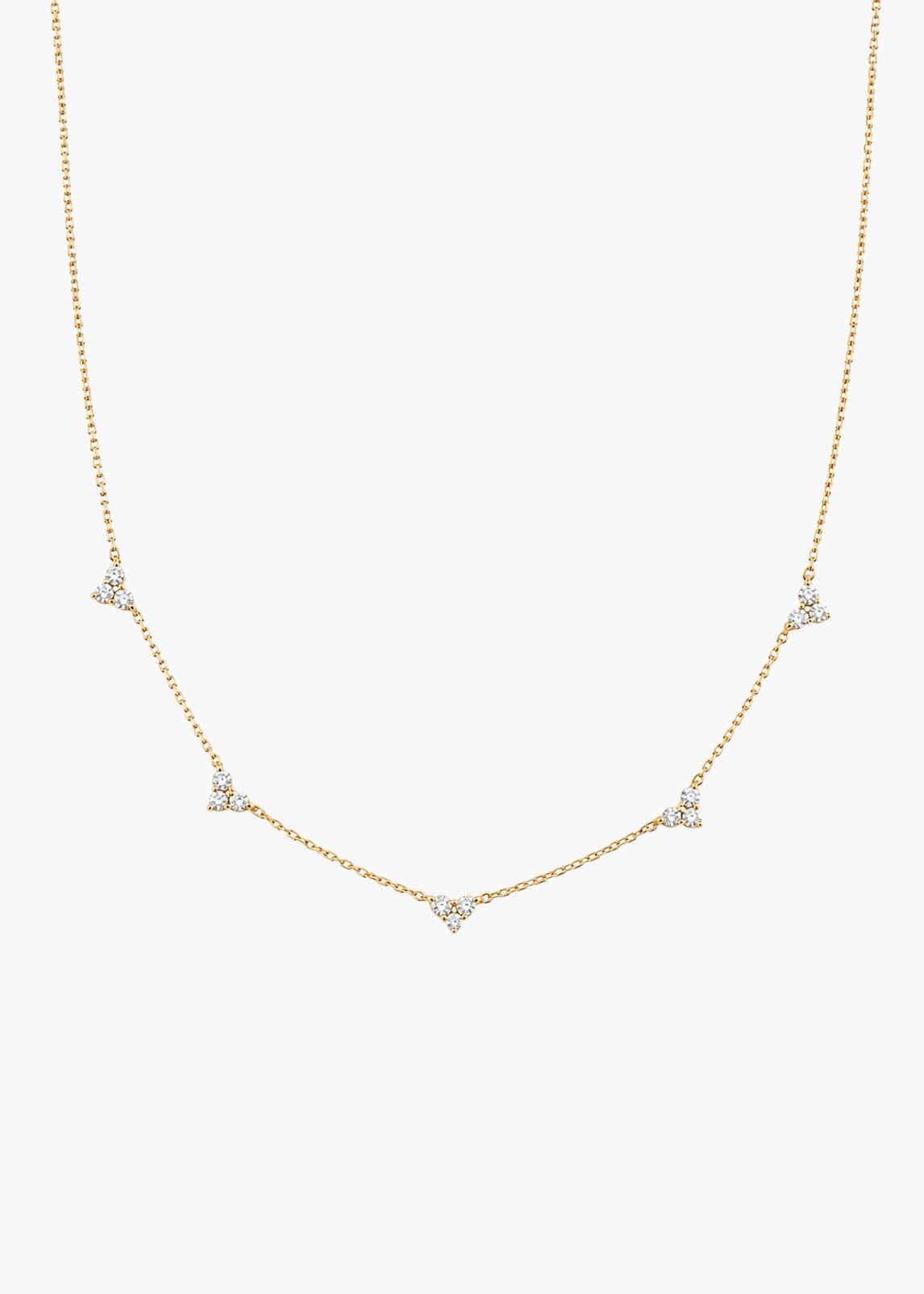 A delicate gold chain necklace featuring five small triangular clusters of clear stones, displayed against a solid off-white background.