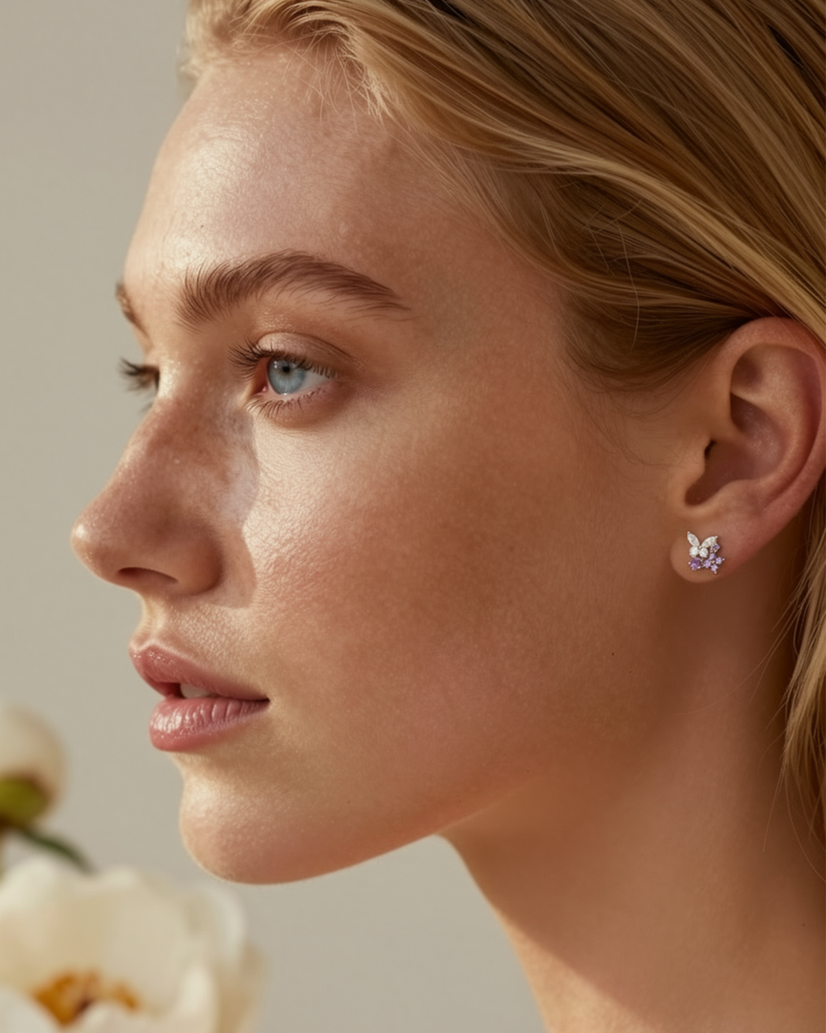 Close-up of a woman wearing a butterfly earring with a neutral background