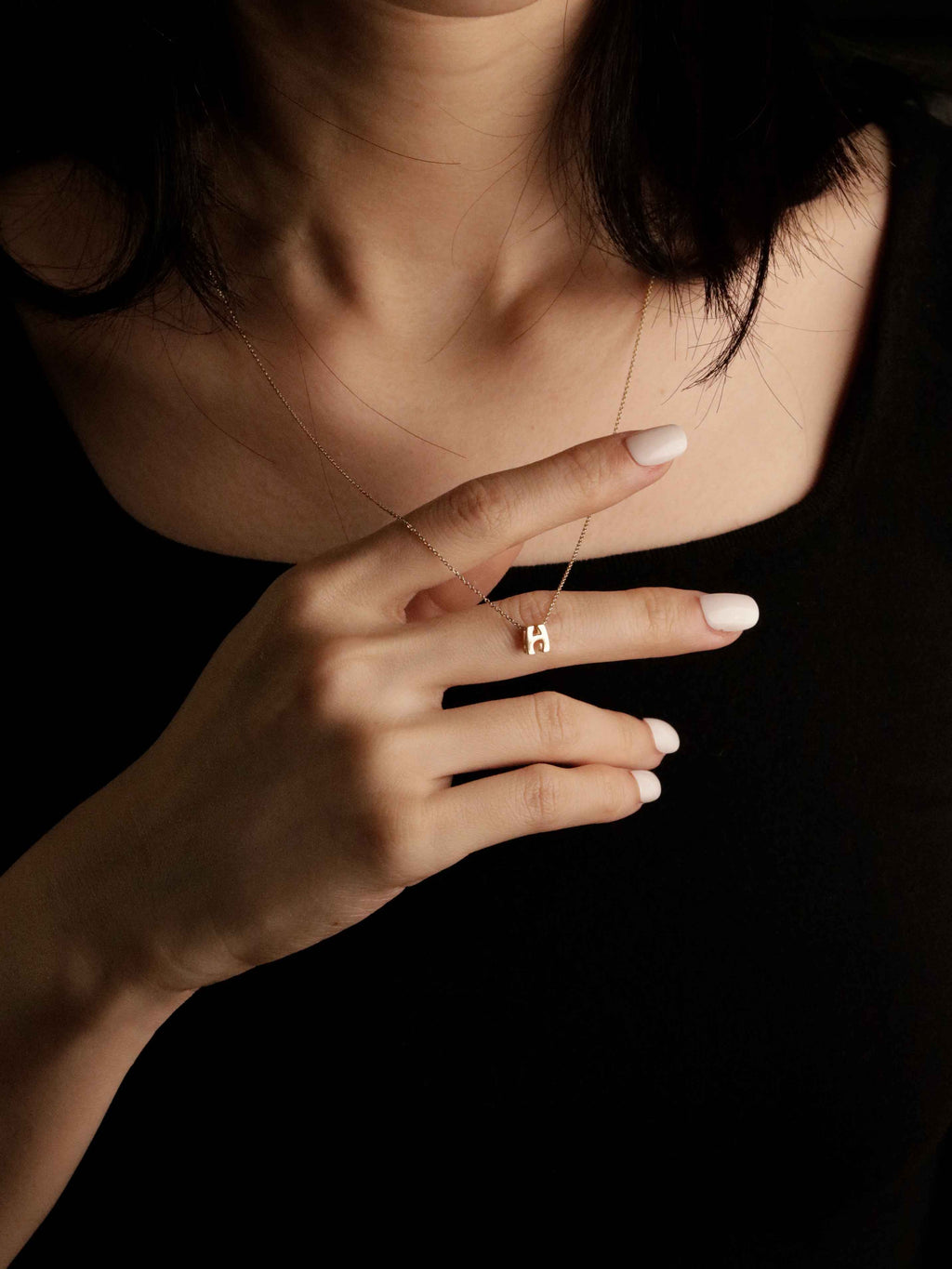 a person wearing a delicate gold necklace with a initial letter