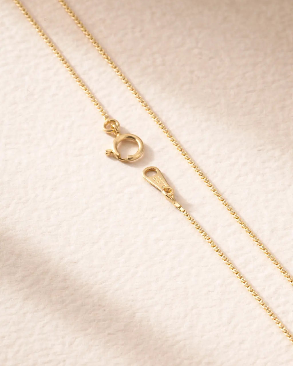 Gold chain necklace on a beige fabric background