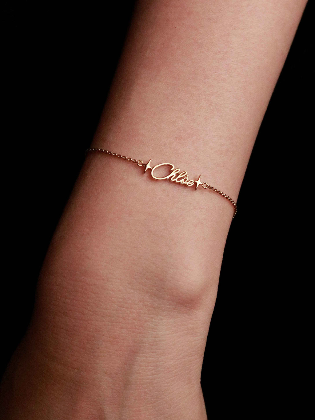 gold bracelet with 'Chloe' on a wrist against a black background