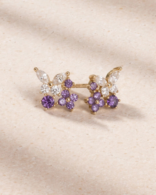 Gold and purple floral earring on a beige background