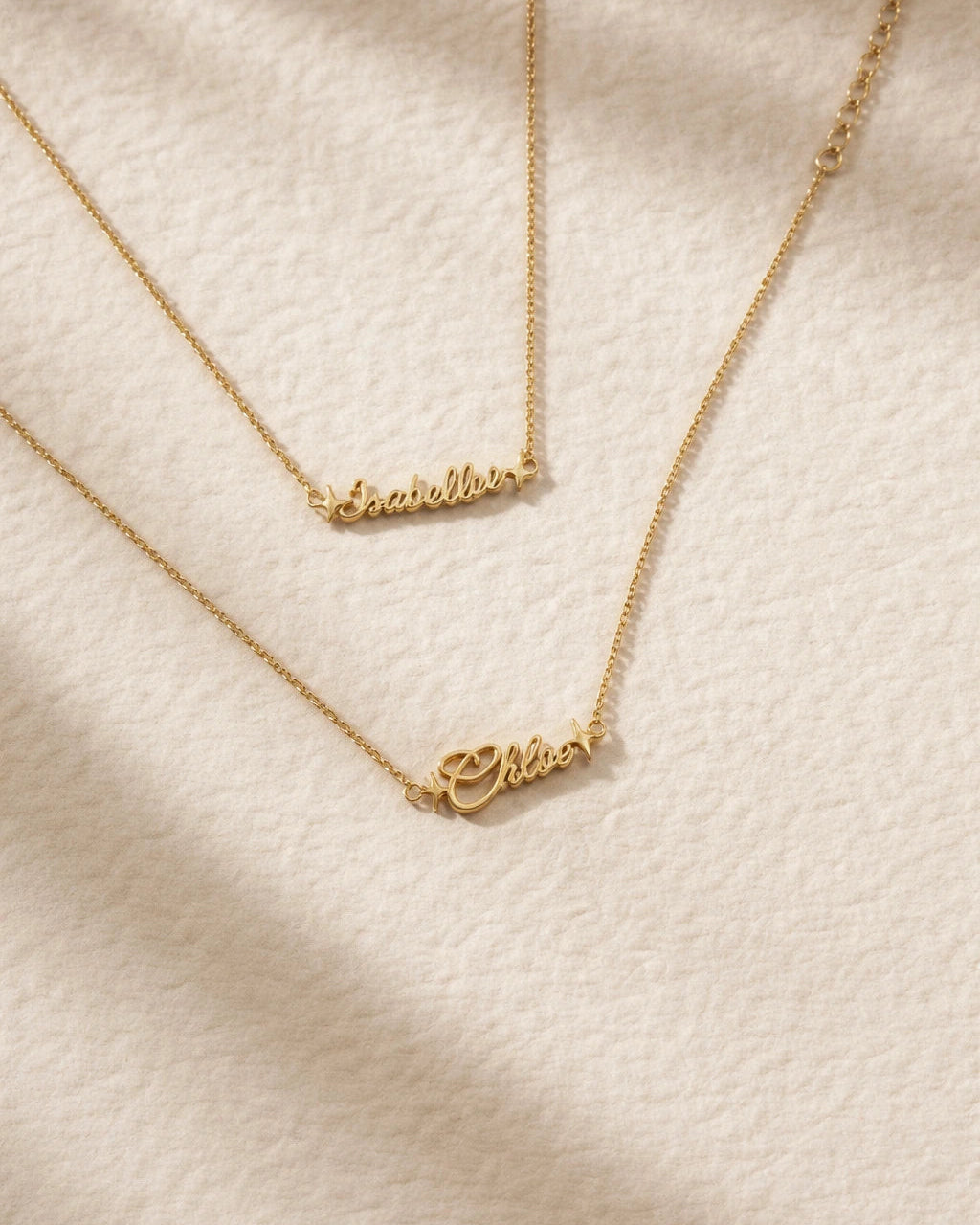 Gold nameplate necklace on a textured beige surface