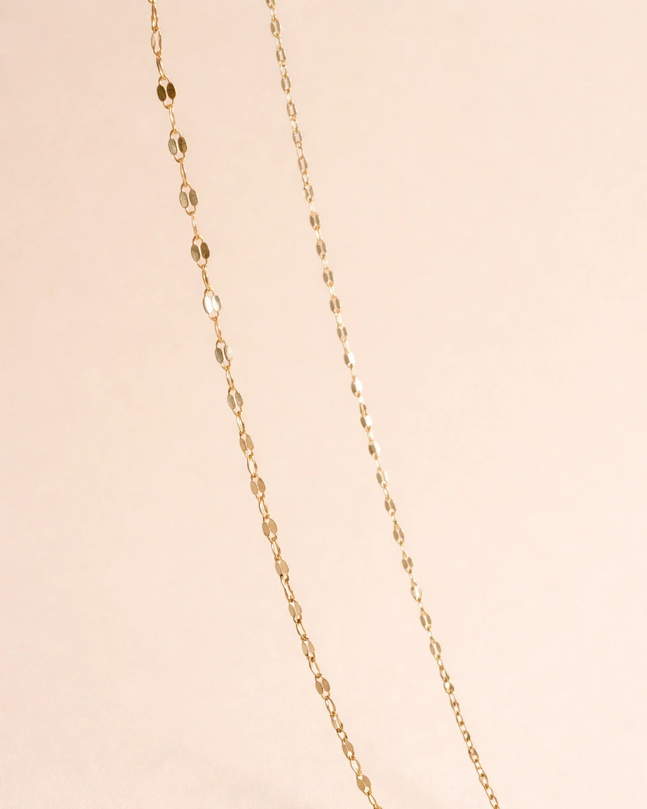 Gold chain necklace on a beige background