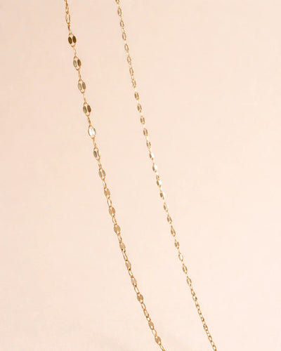 Gold chain necklace on a beige background