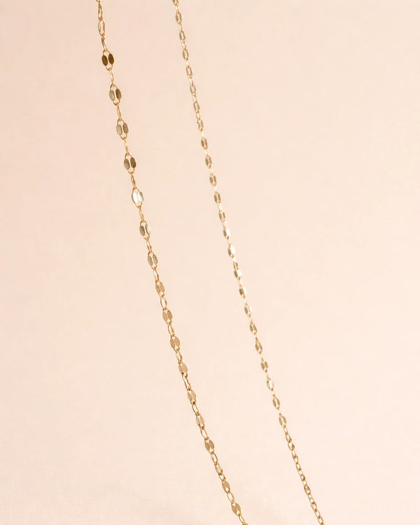 Gold chain necklace on a beige background