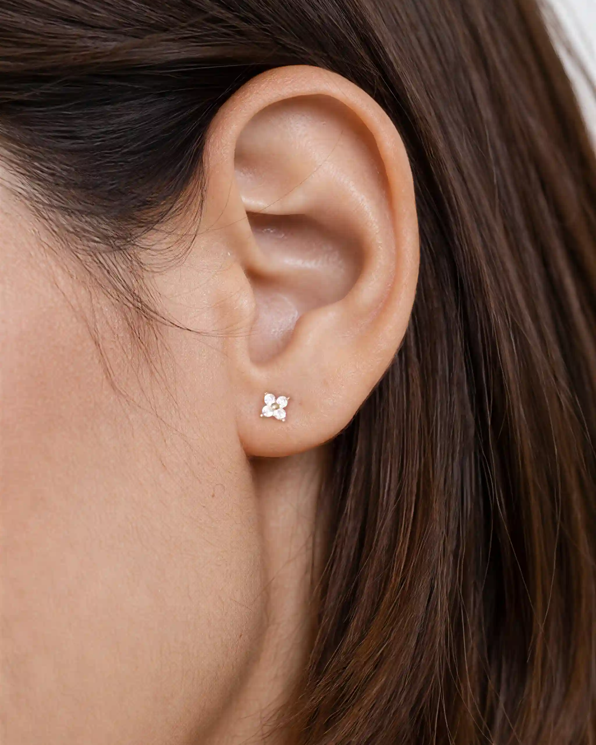 Close-up of an ear wearing a delicate earring with small embellishments.