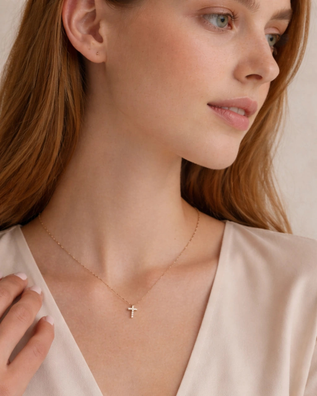 Woman wearing a gold diamond cross necklace with a cross pendant against a neutral background