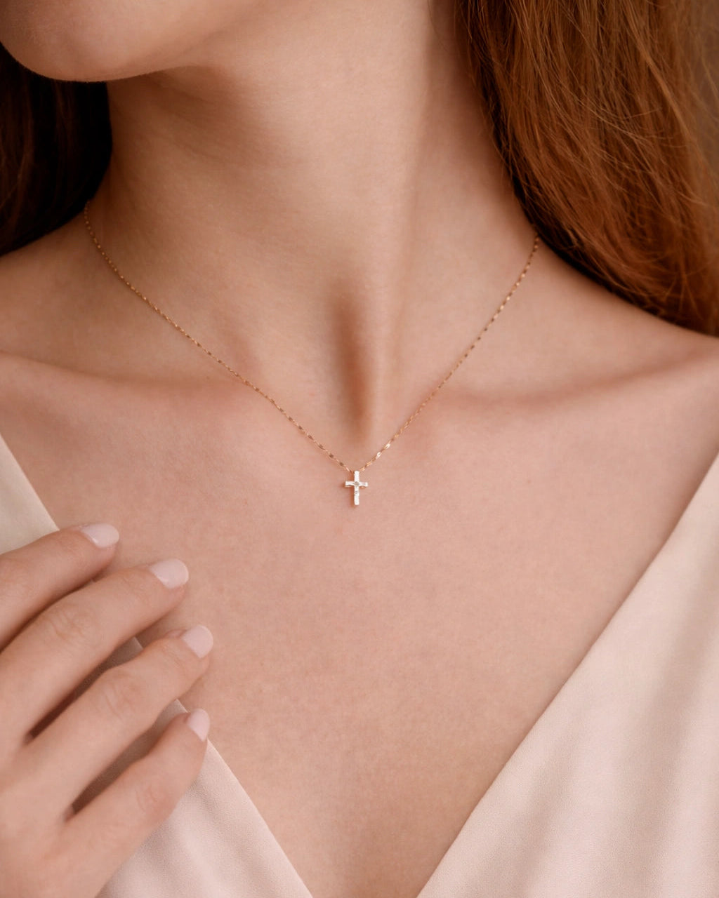 Necklace with a small cross pendant worn by a person