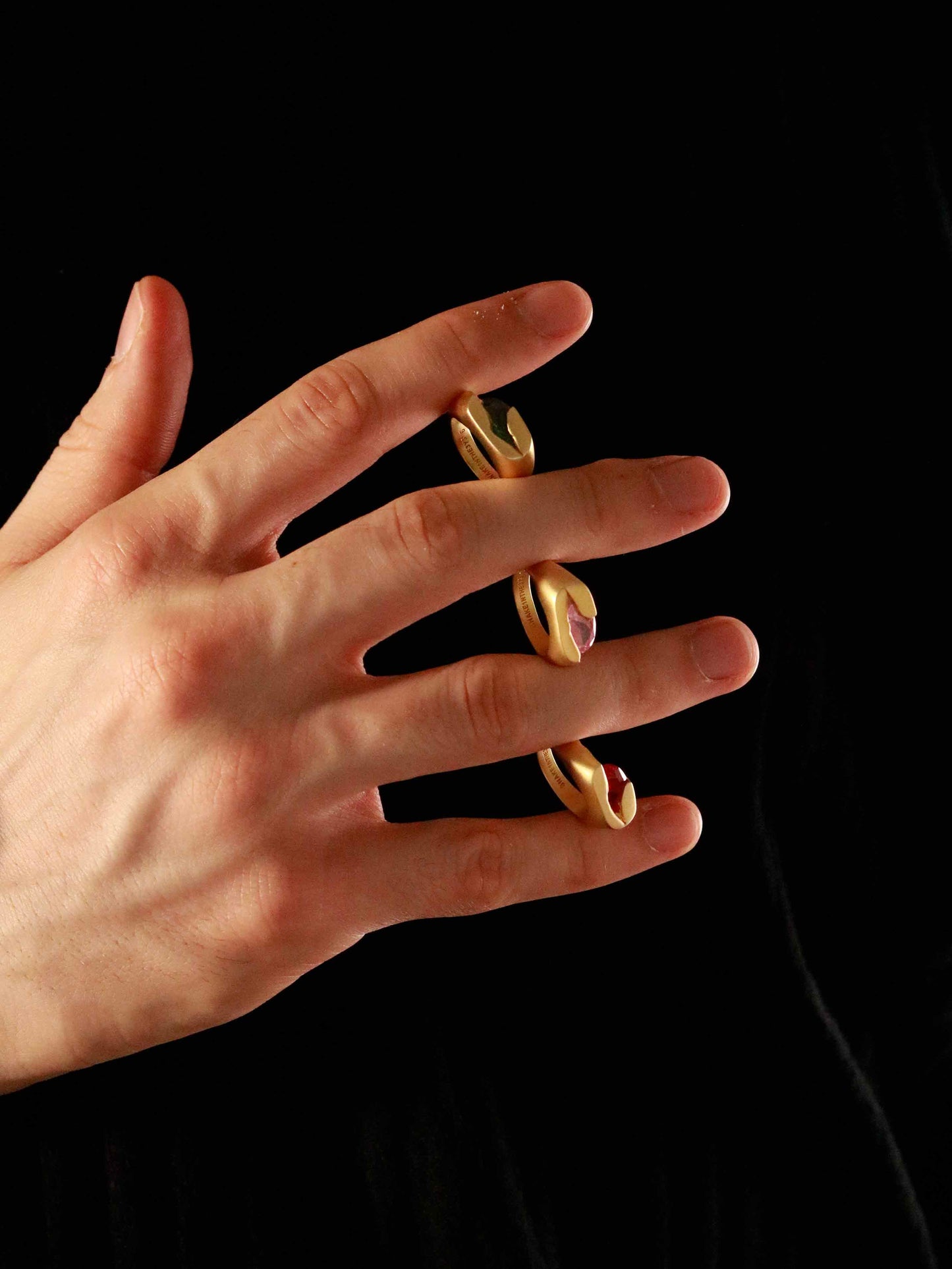 Hand wearing multiple gold rings on a black background