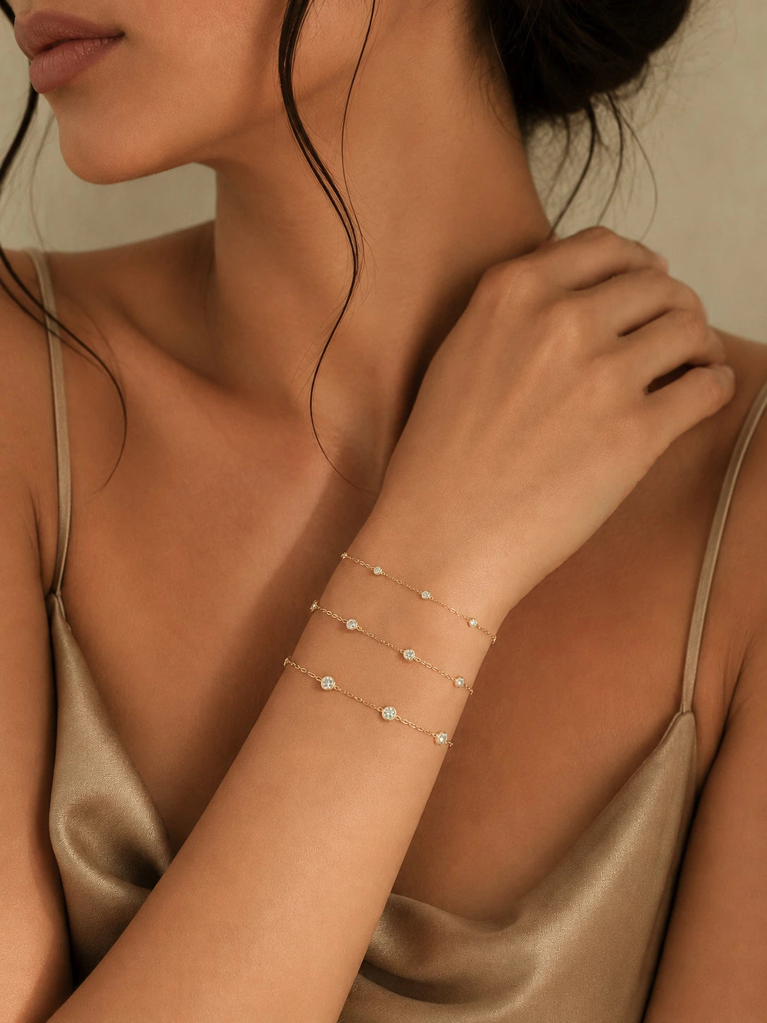 Three 18K solid gold diamond station bracelets in different sizes stacked on wrist, showing small medium and large bezel-set diamond variations