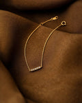 Gold bracelet with a bar clasp on a brown fabric background