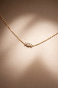 Rose gold necklace with three diamonds on a beige background