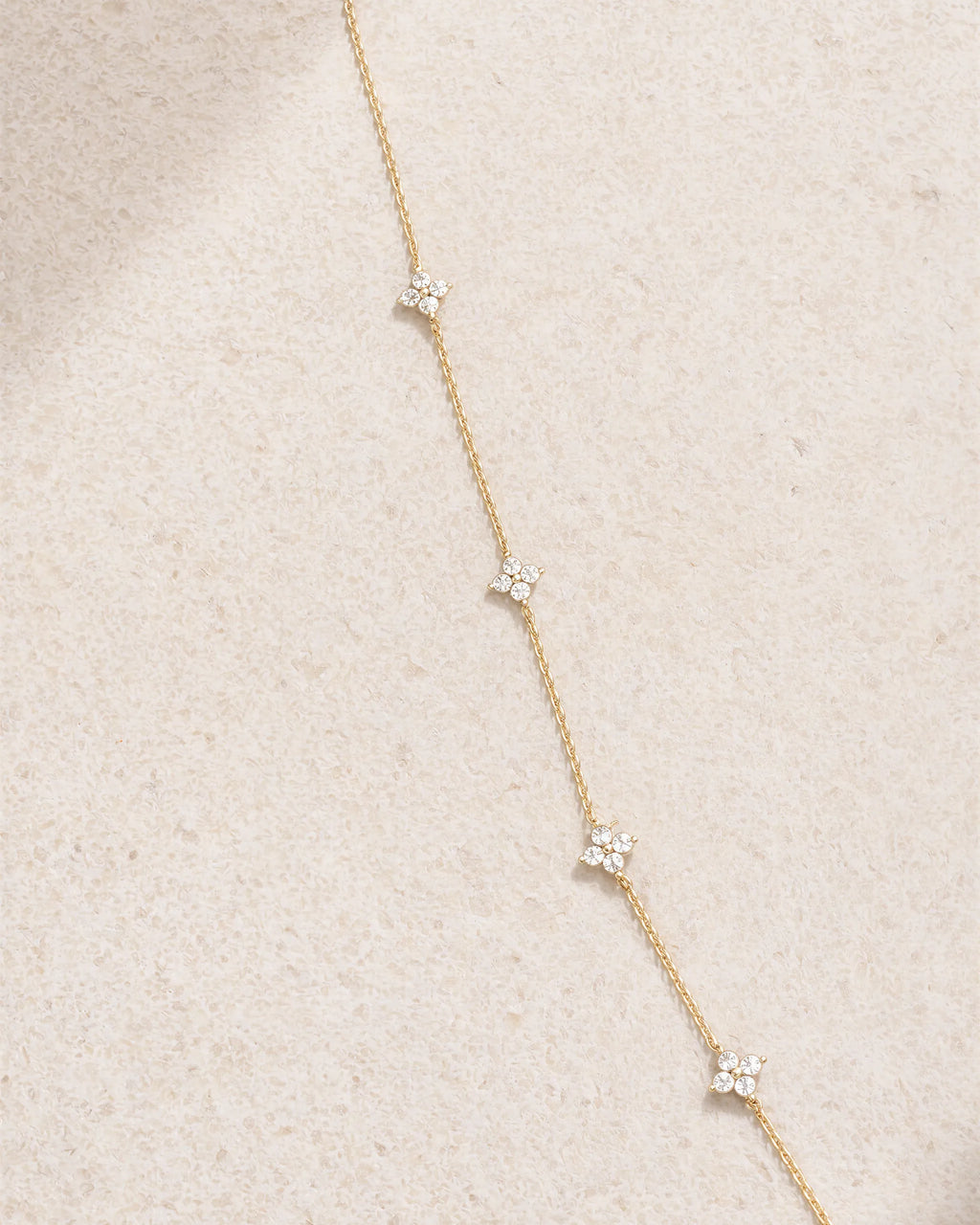 Delicate gold necklace with small diamonds on a beige fabric background