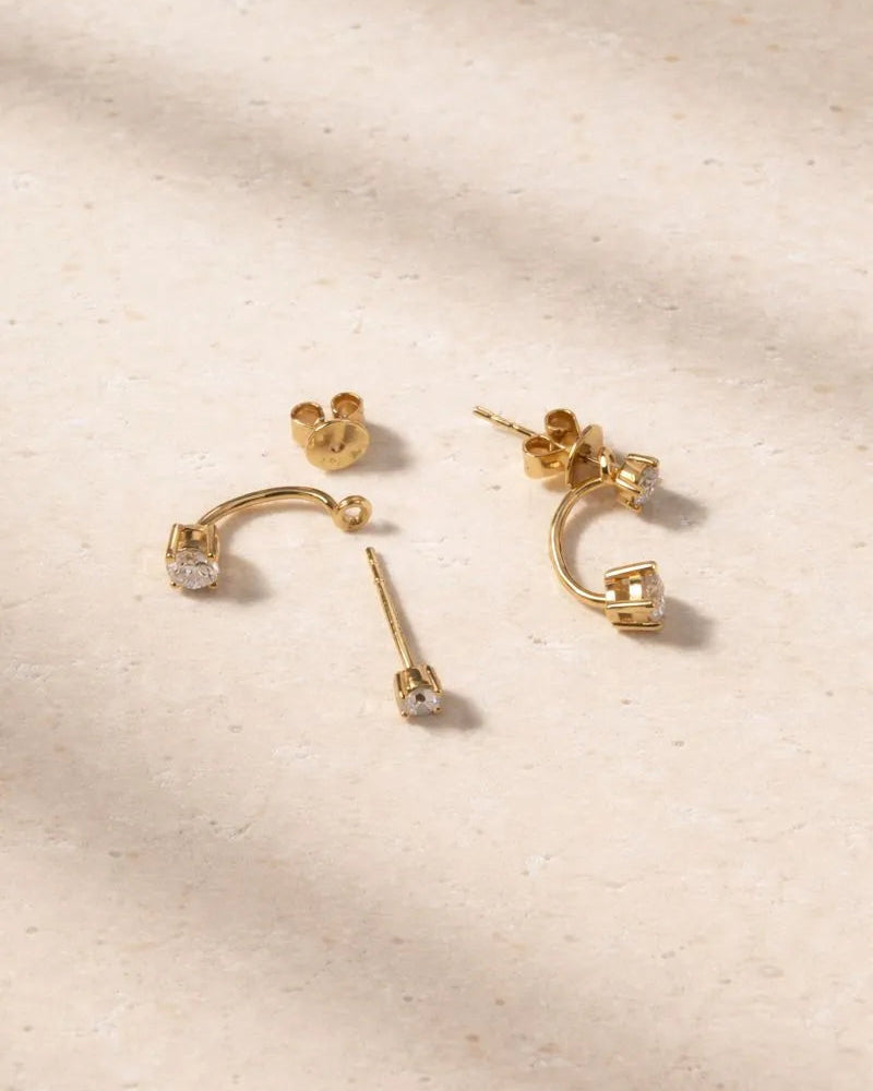 Set of gold earrings on a beige textured background