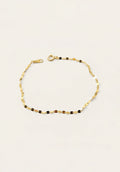 A delicate gold chain bracelet with alternating small gold and dark brown beads, displayed on a clean off-white background.