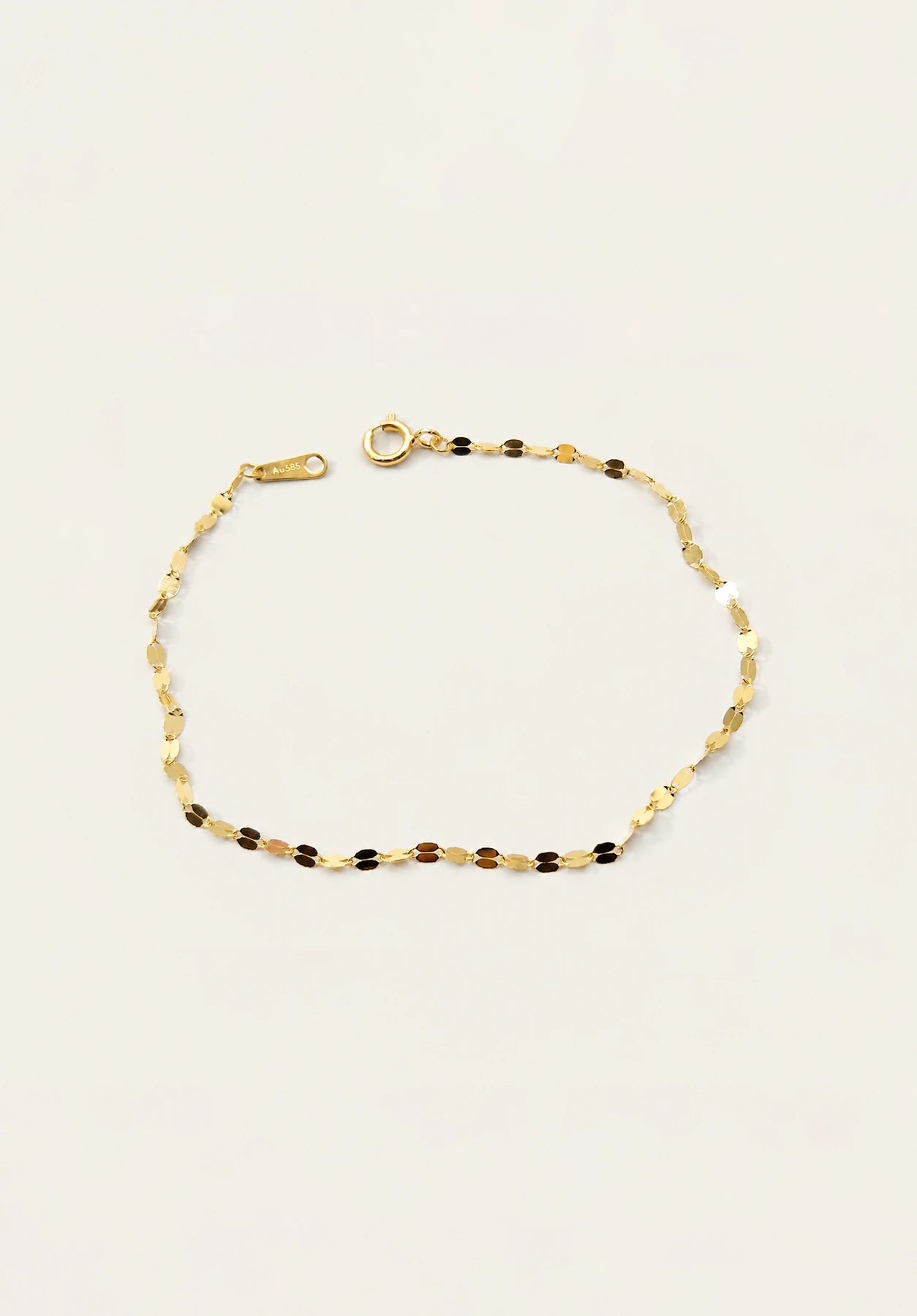 A delicate gold chain bracelet with alternating small gold and dark brown beads, displayed on a clean off-white background.