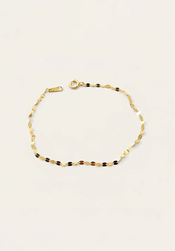 A delicate gold chain bracelet with alternating small gold and dark brown beads, displayed on a clean off-white background.