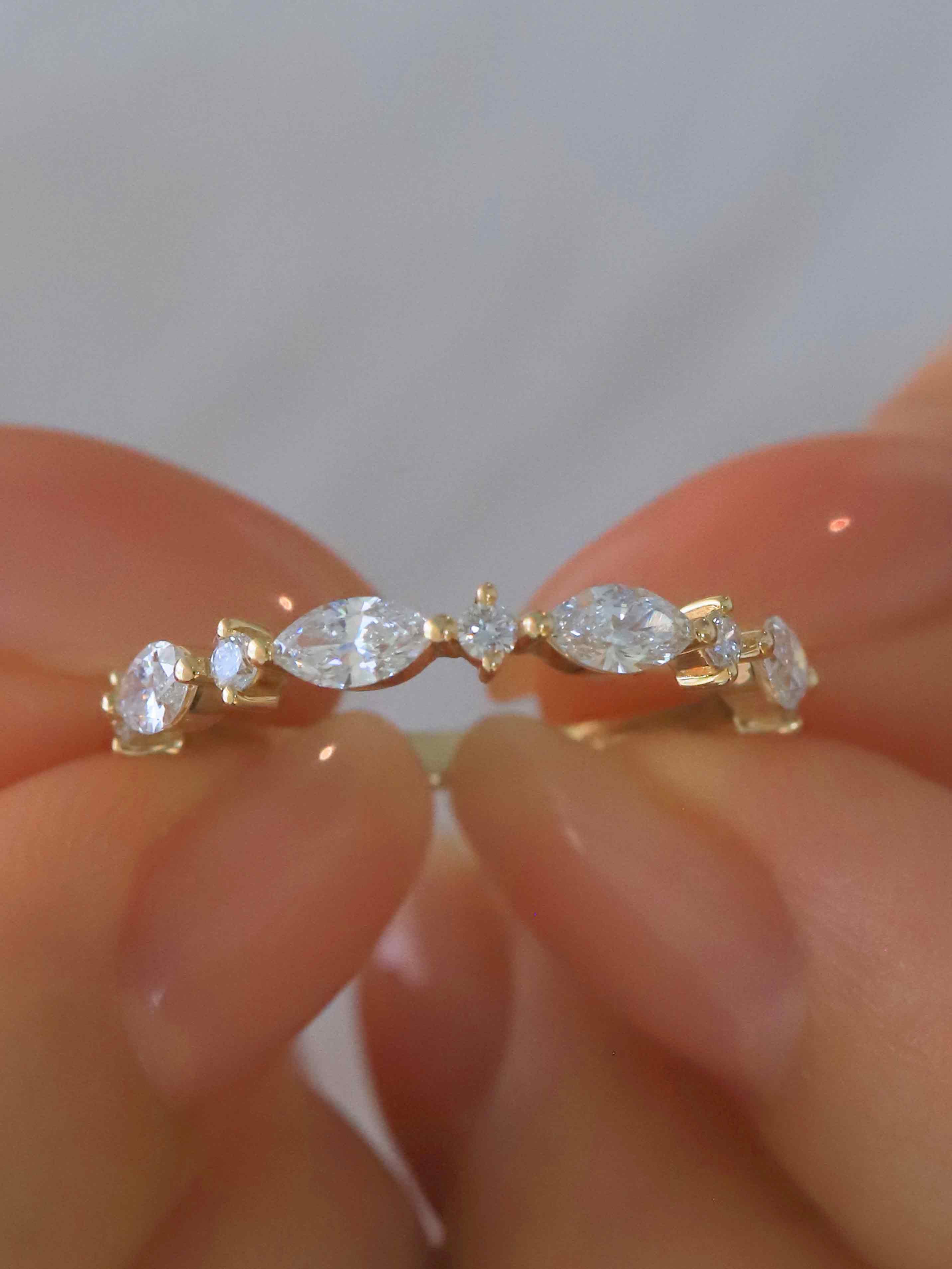 Ethical lab diamond engagement ring on finger - marquise and round cut stones in 14K gold