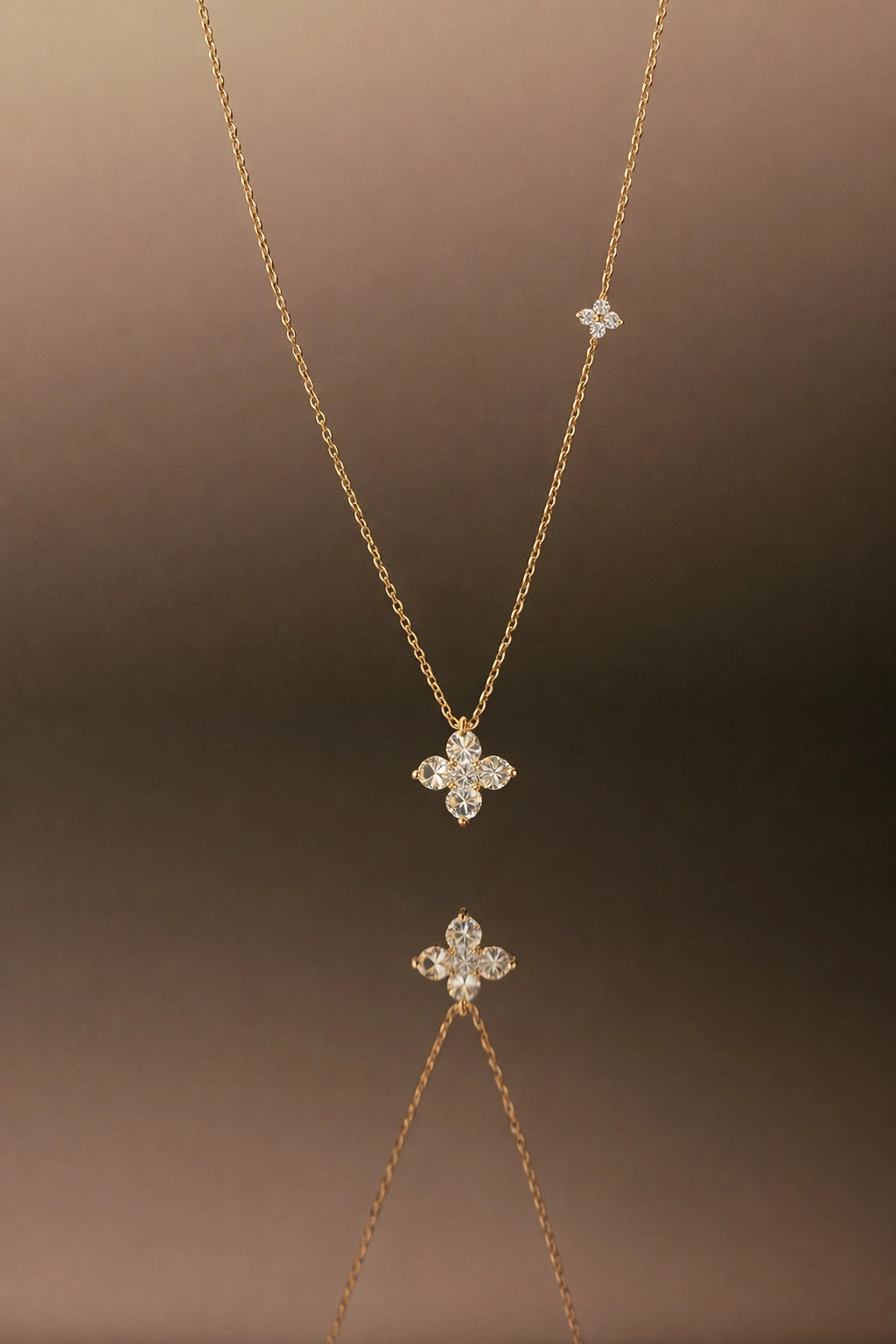 Gold necklace with diamond pendant on a brown background