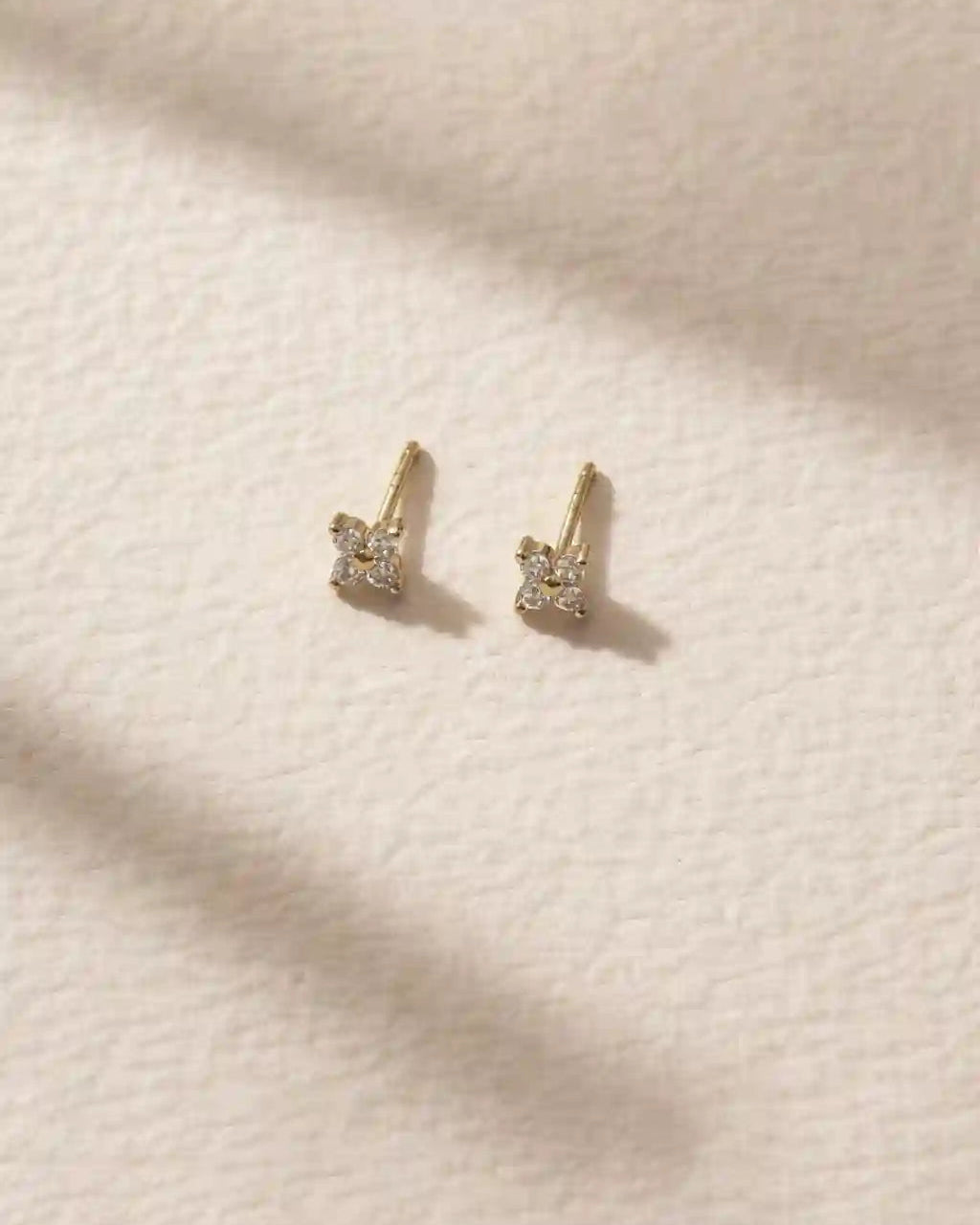 Pair of gold earrings on a beige fabric background