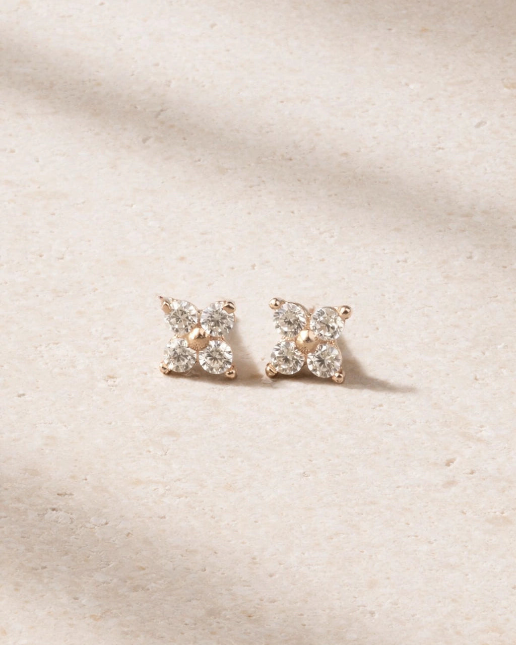 Pair of diamond stud earrings on a beige fabric background