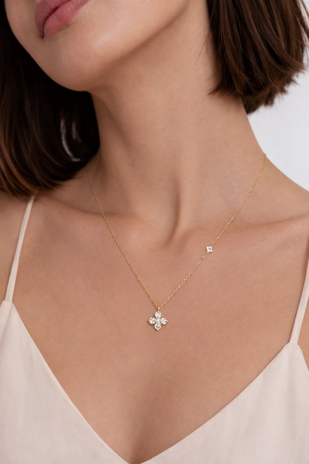 Gold necklace with a floral pendant worn by a person