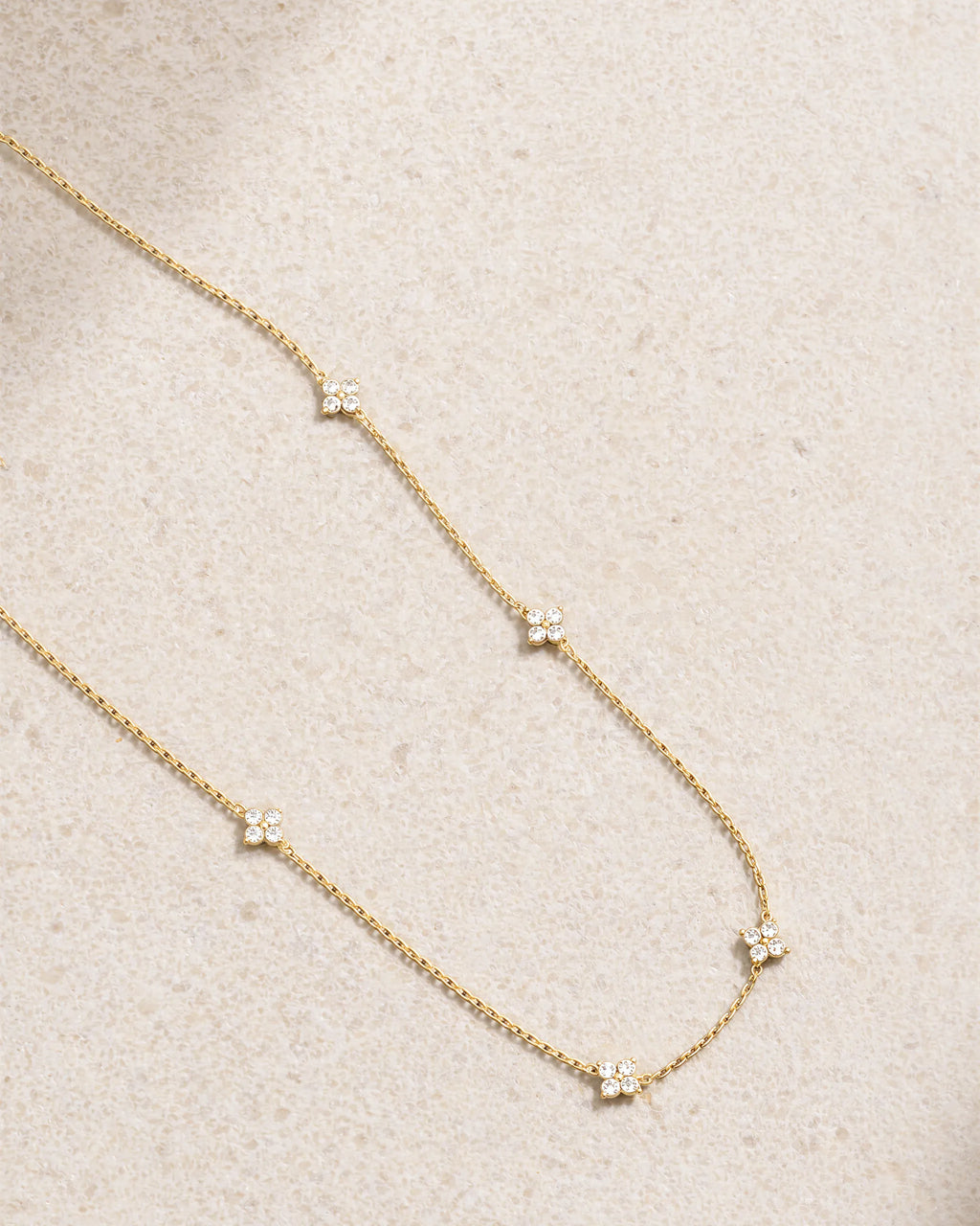 Delicate gold necklace with small diamonds on a beige fabric background