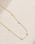 Delicate gold necklace with small diamonds on a beige fabric background